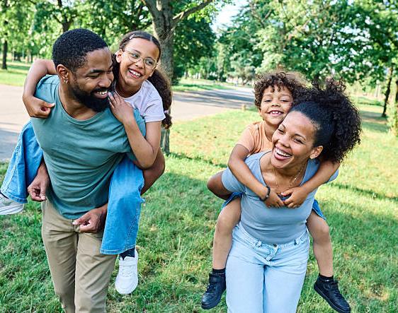 A smiling family laughing together in a sunny park